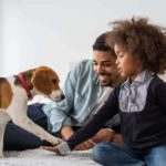 Man and daughter play with pet beagle. CBD oil helps dogs relax and bond with new people.