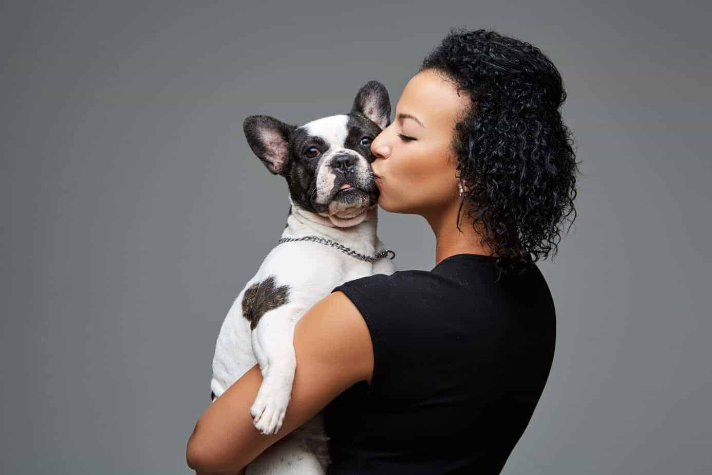 Woman kisses French bulldog. Canadian dog owners use CBD dog treats, sprays, and drops to treat anxiety, arthritis, osteoporosis, and epilepsy.