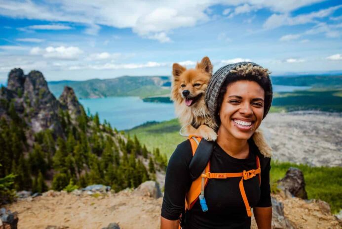 Woman hikes with Pomeranian in her backpack. Include your dog in your eco-friendly life.