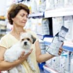 Woman reads information on dog food bag. How to choose dog food: Start by considering your dog's breed, size, and activity level. Then read the ingredients and research the company.