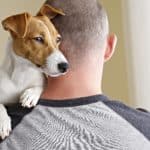 Man cuddles Jack Russell Terrier. If your doctor determines you qualify, he’ll write a letter or ESA certificate to recognize your dog as an emotional support companion.