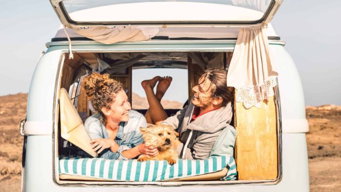 Hipster couple camps with their dog in vintage van. Use this list of tips and tricks to make car camping with your dog go smoothly.