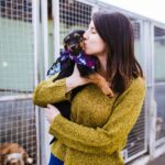 Woman kisses rescue dog at animal shelter.