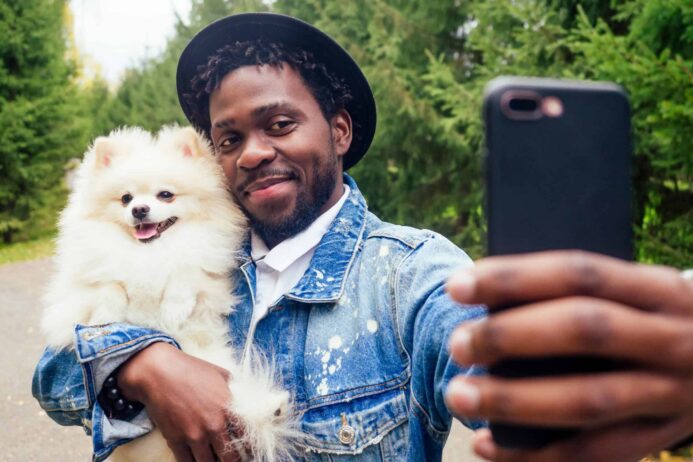 Owner takes selfie while holding his Spitz dog. Creating worthy social media content with animals is easier, as they all are cute and beautiful by default.