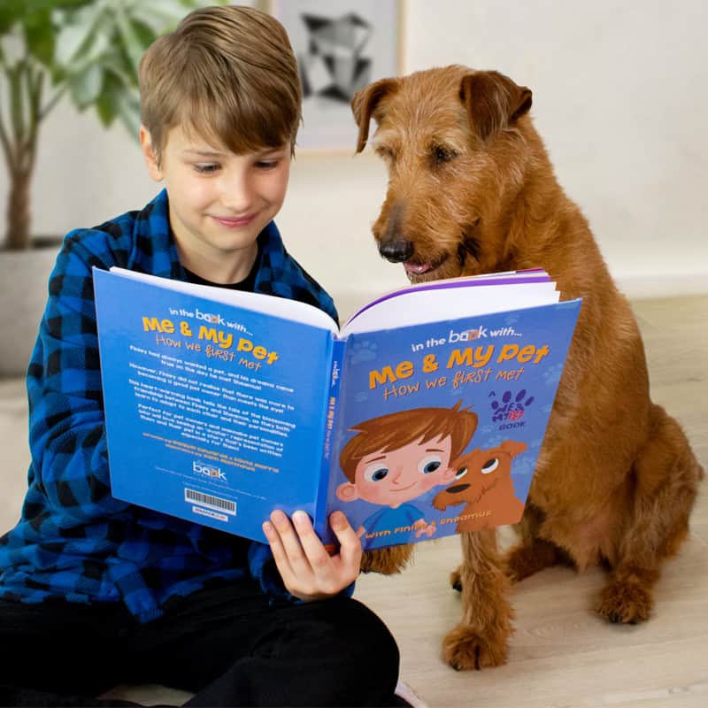 Boy reads book to dog. Scientific studies explore the advantages of bringing up children and dogs together and how it can be mutually beneficial.