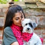 Woman wears scarf that matches her dog's bandana. Choose among perfect gift ideas for pet parents: automated toys, matching outfits, custom portraits, or custom collars and leashes.