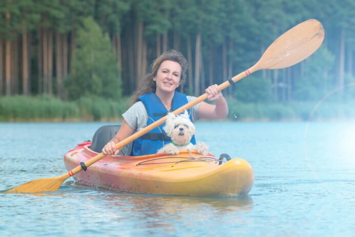 Woman paddles kayak with shih tzu. Photo for safely kayak with your dog post.