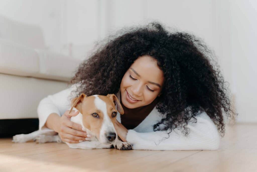 Woman cuddles with dog on the floor. Photo for signs you're a crazy dog person post.
