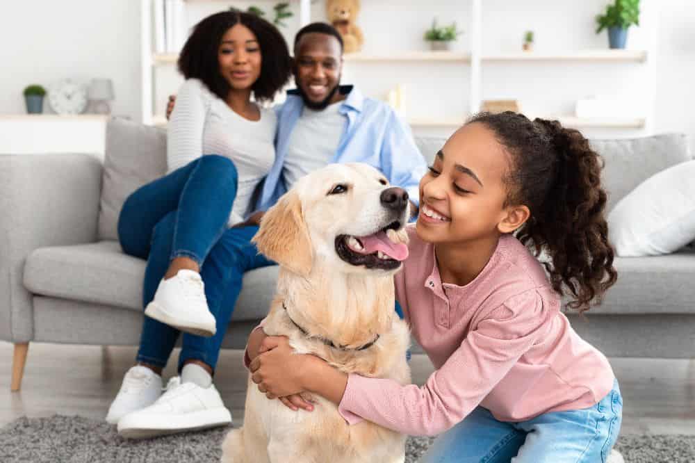 Girl cuddles with Labrador Retriever while parents watch. Use these tips to create a furever home for your new pet. Get the right supplies, establish a schedule, and make your home safe and secure.