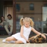 Little girl pets German Shepherd. Before you adopt a furry companion, evaluate your family’s lifestyle and daily routine. Consider factors such as activity level, available space, and time commitment.