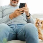 Man looks at a smartphone while a Chihuahua sits at his side. Discover 10 smartphone apps that make life easier for you and your dog. Use convenient pet care apps to simplify your daily routine.