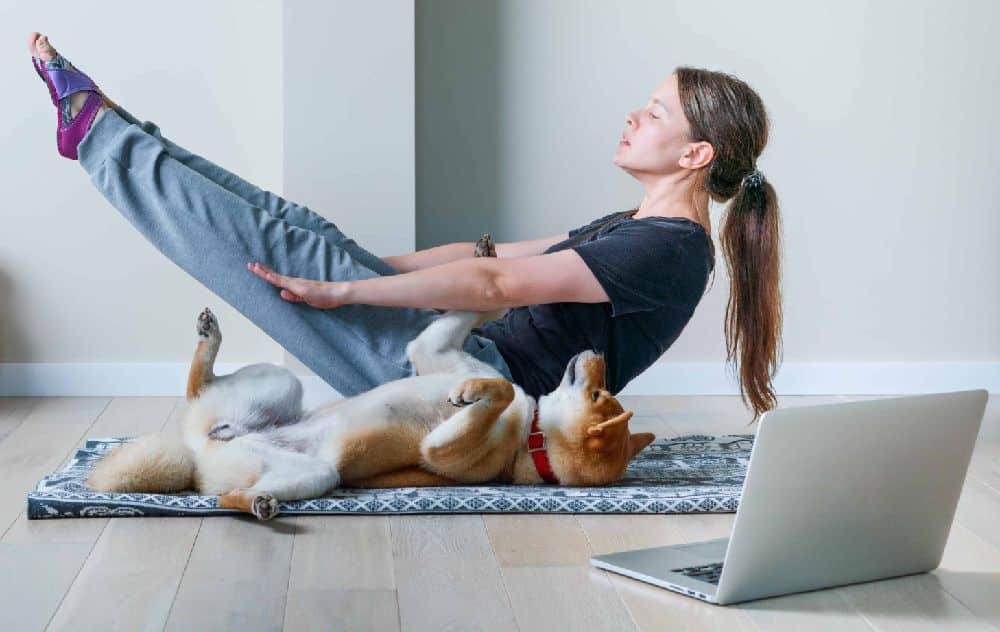 Woman does yoga with her dog. ease their anxiety. Dogs offer college students unconditional affection, companionship, and a sense of serenity that can aid them in managing stress levels.