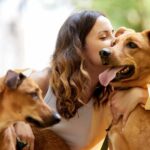 Woman hugs dog. Fostering dogs can benefit the dog and caregiver. First, consider whether or not you have the time and space to properly care for them.