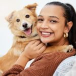 Happy woman cuddles with dog. Dog ownership health benefits include releasing endorphins.