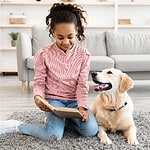 Girl reads to Golden Retriever while sitting on rug. Illustration for home improvements article.