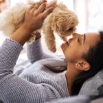 Owner cuddles puppy. Discover tips to manage dog ownership on a budget.